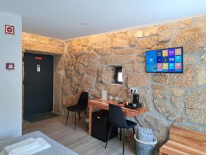 een kamer met een stenen muur met een tafel en stoelen bij Agrafonte in Paços de Ferreira