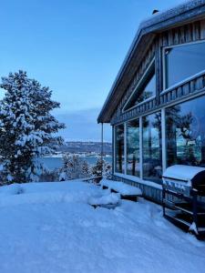 een huis met sneeuw op de grond ervoor bij Cozy cabin HYLLA in Hamnvågnes