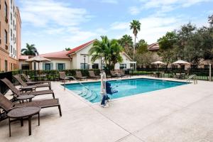 uma piscina com espreguiçadeiras e um resort em Homewood Suites by Hilton West Palm Beach em West Palm Beach
