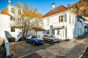 two cars parked in front of a white house at Central first floor apartment in Bergen