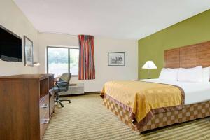 a hotel room with a bed and a television at Days Inn & Suites by Wyndham Kansas City - Chiefs Stadium in Kansas City