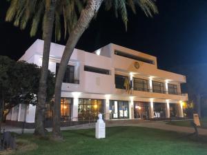 un grand bâtiment blanc avec des palmiers la nuit dans l'établissement Patios de la Carmela, à Isla Cristina