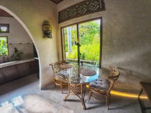 D'Sari Undisan Houses - Abeona Private Villa في Undisan: غرفة طعام مع طاولة زجاجية وكراسي ونافذة