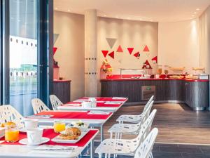 un restaurante con sillas blancas y mesas con comida. en Mercure Toulouse Sud, en Toulouse