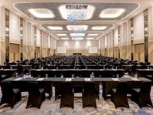 une grande salle remplie de tables et de chaises dans l'établissement Novotel Samator Surabaya Timur, à Surabaya