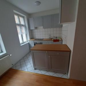 una pequeña cocina con armarios blancos y una ventana en FeWo Dis, en Zeitz
