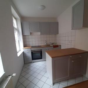 a small kitchen with white tile floors and white cabinets at FeWo Dis in Zeitz
