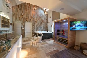 Habitación con baño con bañera y TV. en Instinct - Jacuzzi, Sauna, Apéritif dînatoire et Petit déjeuner, 