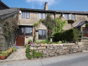 a stone house with a stone wall and flowers in front at 2 Bed in New Mills 75029 in Mellor