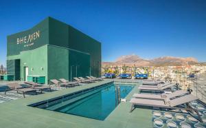 una piscina con tumbonas y un edificio en Barceló Benidorm Beach - Adults Recommended, en Benidorm