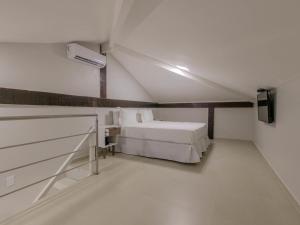 Habitación blanca con cama y TV en Hotel Ilha Branca Inn en Búzios