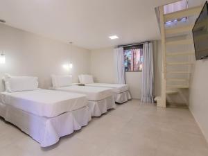 a bedroom with two beds and a book shelf at Hotel Ilha Branca Inn in Búzios