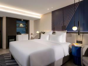 a large white bed in a hotel room at TRIBE Living Bangkok Sukhumvit 39 in Bangkok