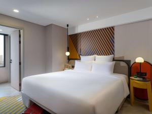 a large white bed in a hotel room at TRIBE Living Bangkok Sukhumvit 39 in Bangkok