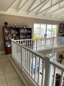 a white staircase in a living room with a balcony at Calm Waters Guesthouse: Robberg Room in Plettenberg Bay