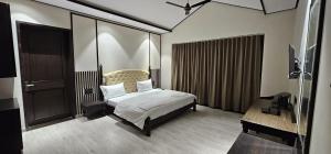 a bedroom with a bed and a desk and a television at THE PREMIER GIR RESORT in Sasan Gir
