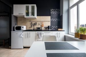 a kitchen with white cabinets and a black wall at Kawiory 2/22 in Krakow