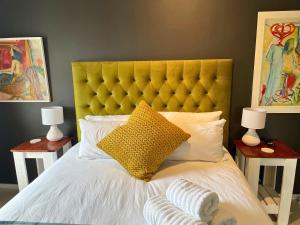 a bed with a yellow headboard and two night stands at Calm Waters Guesthouse: Robberg Room in Plettenberg Bay