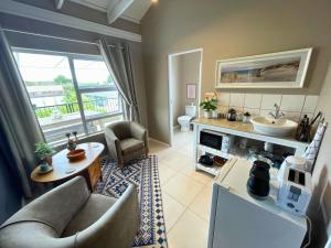 Calm Waters Guesthouse: Robberg Room في بليتنبيرغ باي: غرفة معيشة مع أريكة ومغسلة