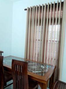 a dining room table with chairs and a window with curtains at Unic Residence And Transit Hotel in Katunayake