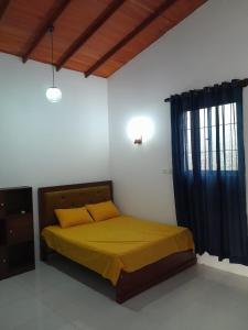 a bedroom with a bed with yellow sheets and a window at Unic Residence And Transit Hotel in Katunayake