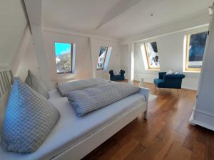 una camera da letto con un grande letto bianco con cuscini blu di Penthouse über den Dächern Badenweilers a Badenweiler