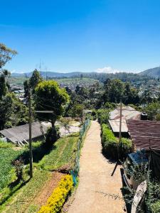 a dirt road leading to a village with mountains in the background at Micro wood cabana in Nuwara Eliya