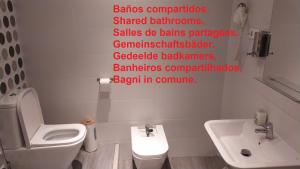 y baño con aseo blanco y lavamanos. en Pensión Manoli, en Bilbao