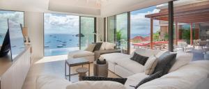 una sala de estar con muebles blancos y vistas al océano. en Luxury Vacation Villa 4, en Gustavia
