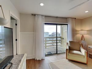 a living room with a chair and a sliding glass door at Lighthouse Point 7c in Tybee Island