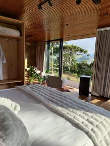 a bedroom with a large bed with a large window at Jardim das Pedras in Bom Jardim da Serra