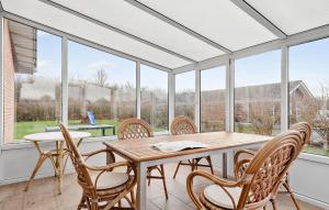 einen Wintergarten mit einem Tisch, Stühlen und Fenstern in der Unterkunft Four-Bedroom Holiday Home In Sydals in Skovbyballe
