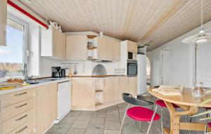 eine Küche mit Holzschränken und einem Tisch mit Stühlen in der Unterkunft Four-Bedroom Holiday Home In Sydals in Skovbyballe