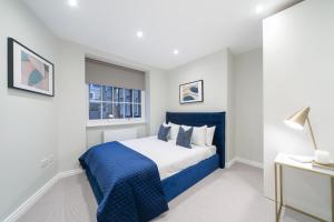 a bedroom with a blue and white bed and a window at Urban Chic - Acre in London