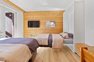 a bedroom with two beds and a tv on the wall at Retraite alpine, studio paisible et rénové in Leukerbad