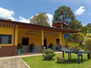 um edifício amarelo com uma mesa em frente em chácara vovó Lucia em Barreira