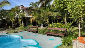 zwei Bänke und ein Pool vor einem Haus in der Unterkunft Les Varangues Rodrigues in Rodrigues Island