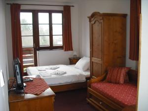a bedroom with a bed and a desk and a window at Sport hotel POMI in Harrachov