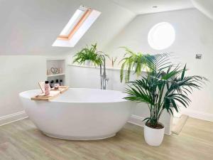 a large white bath tub in a bathroom with plants at Meadow Guesthouse - Private Hot Tub in Rossett