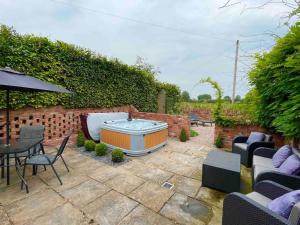 a patio with a hot tub and a table and chairs at Meadow Guesthouse - Private Hot Tub in Rossett