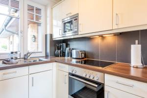 Una cocina con gabinetes blancos y un horno de estufa. en Haus Maybachstraße, en Westerland