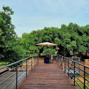 une promenade en bois avec une table et un parasol dans l'établissement Casa Container Camisão, à Camisão