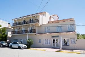 a white house with a car parked in front of it at SH Hotel & Spa de Mar Samay Huasi in Puerto Madryn