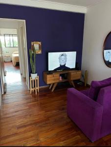 sala de estar con sofá púrpura y TV en Alójate en Pichincha Dpto completo en el corazón de Pichincha, el barrio mas lindo de Rosario en Rosario