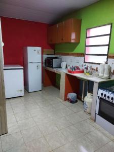 una cocina con paredes verdes y rojas y electrodomésticos blancos en Rancho Abuela Angela, en Ayolas