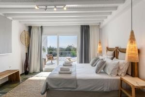 a white bedroom with a large bed and a balcony at Mykonos Lagom in Mikonos