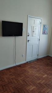 a flat screen tv on a wall next to a door at 2 quartos Icaraí in Niterói
