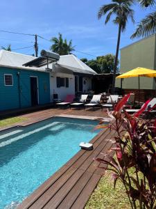 einen Pool mit einer Holzterrasse neben einem Haus in der Unterkunft Maison avec piscine chauffée - 8 personnes - Sud Réunion in Saint-Joseph