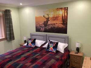 a bedroom with a bed with a painting on the wall at Taigh Sealladh Fèidh B&B in Fort Augustus