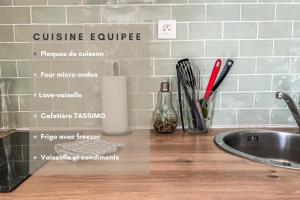a kitchen counter with a sink and a wall with a cuisineureure sign at Le Gite 3 - Studio confort, 10min Golfech in Malause